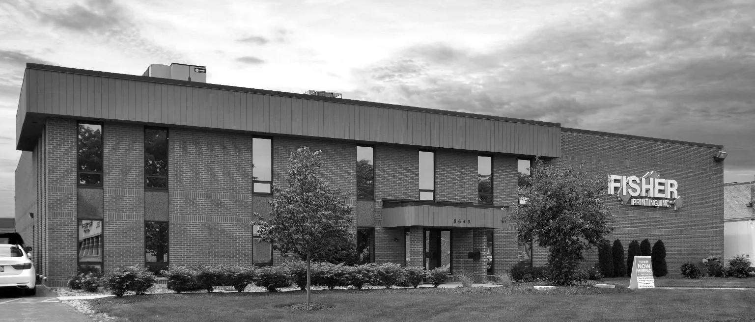 A brick commercial building with tall windows, and a sign displaying Fisher logo.