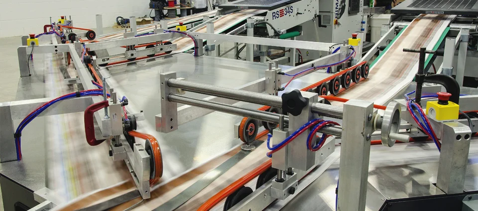 A fast-moving printing press with paper sheets, surrounded by metal rails and machinery.